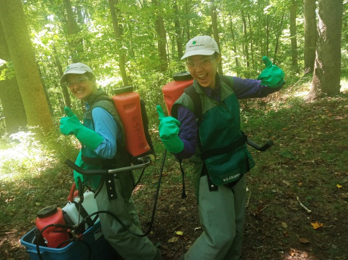 Mia and her friend give an enthusiastic thumbs up to the camera amidst the trees in the Delaware State Parks
