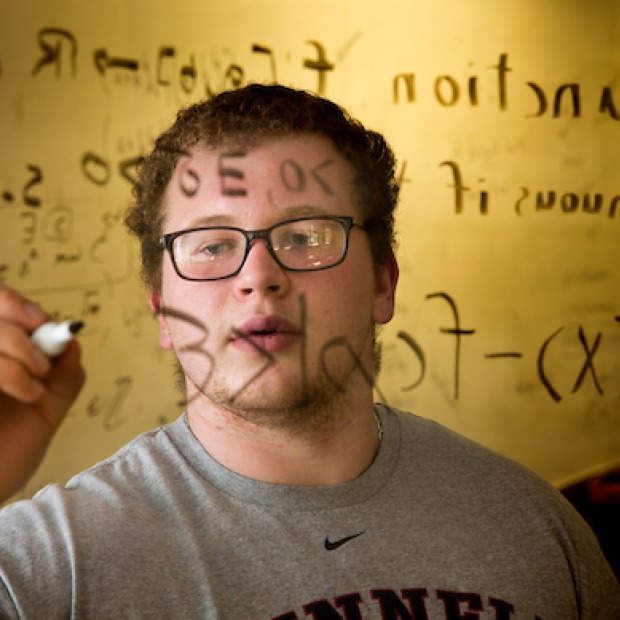 Student calculates math problem on clear marker board
