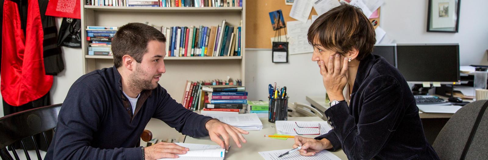 student and professor discuss project at desk