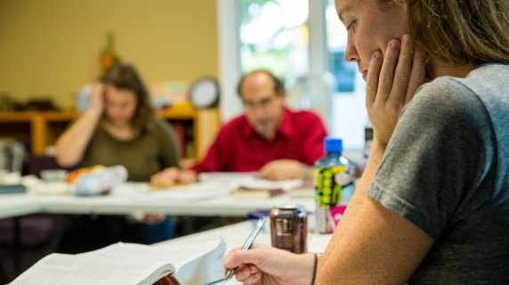 girl with pen studying with book in front 