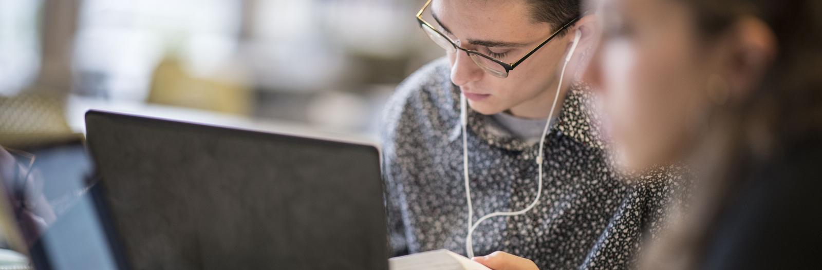 Student studying in Burling library with ear buds in