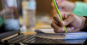Student taking notes on paper during class
