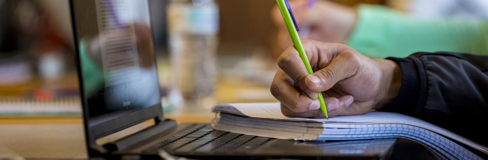 Student taking notes on paper during class