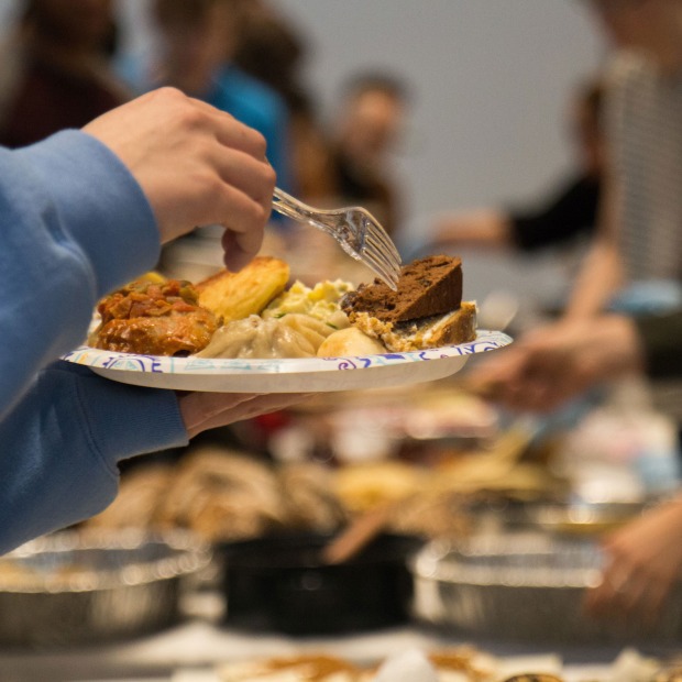 plate full of food held over tables laden with dishes