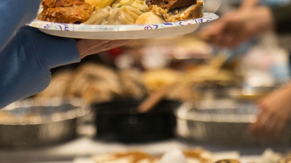plate full of food held over tables laden with dishes