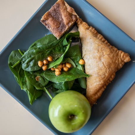 Marnie's lunch a spinach salad, a turnover, a green apple, and a dessert bar