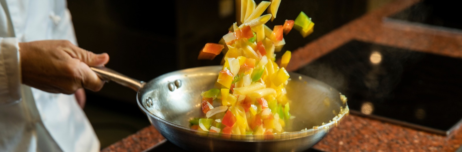 Chef flipping pasta dish in skillet