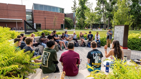 Students have class outdoors near blackboard outside HSSC