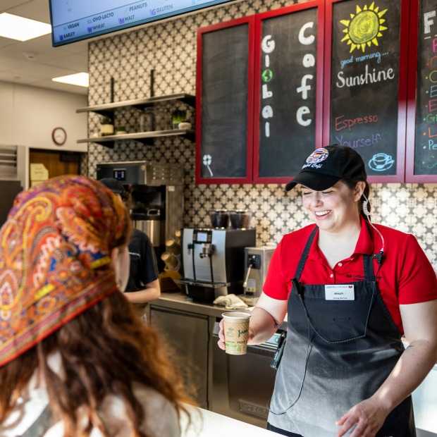 Cafe employee hands drink to a customer