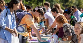 SO 4 Several students crowd tables at an outdoor fair