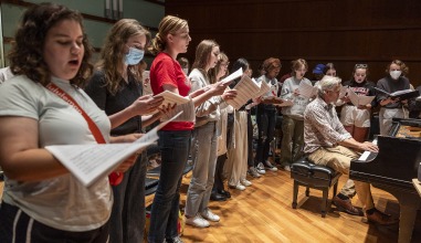 The Grinnell Singers rehearse with Director John Rommereim at the grand piano.