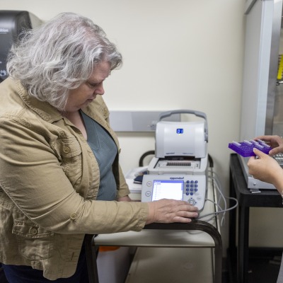 A woman assists a student in setting up a laboratory instrument for an experiment.