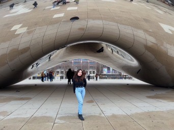 Young woman poses with The Bean sculpture in downtown Chicago