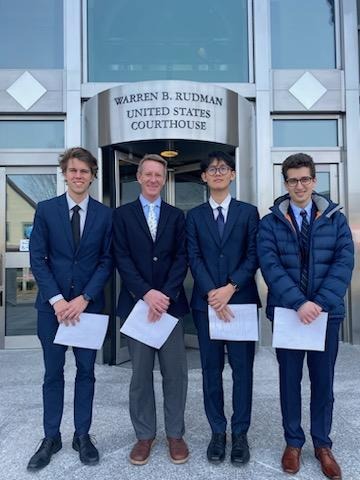 For young men in suits stand in front of the courthouse