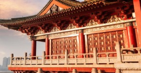 A traditional red Chinese building in foreground and skyscrapers in background
