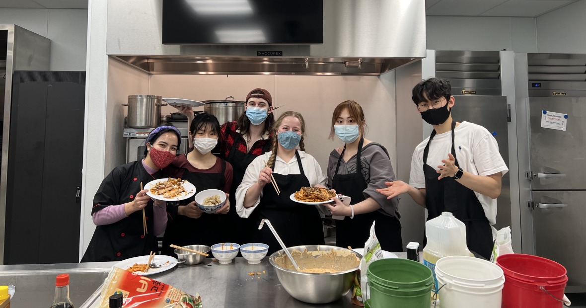 students in kitchen presenting a variety of desserts