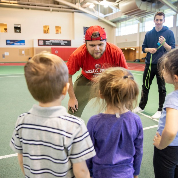 Coaching student talks to three young athletes
