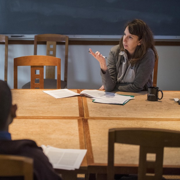 Students and a professor talk around a table