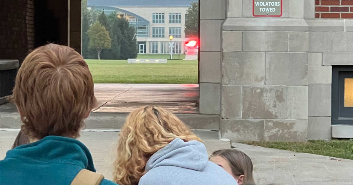 Students view the early morning sun through the arches of East Campus, framed by the arches of North Campus