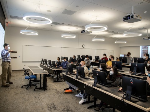 A teacher stands before students in a classroom