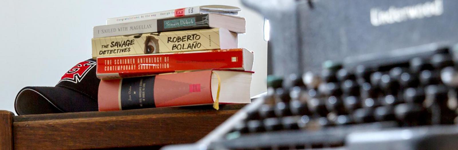 books on a table beside a typewriter