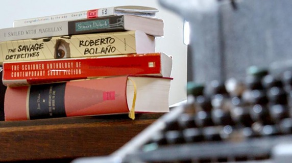 books on a table beside a typewriter