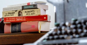 books on a table beside a typewriter