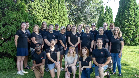 adult professionals in matching black t-shirts smile for a group photo