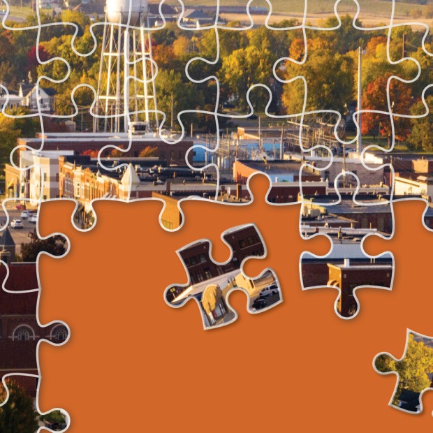 An aerial view of Grinnell is depicted as a partially completed jigsaw puzzle