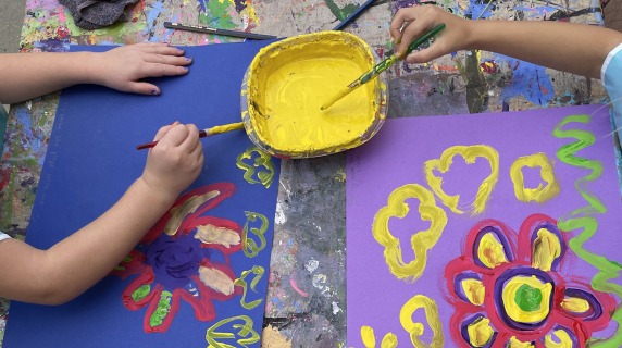 Overhead view of two children painting flowers