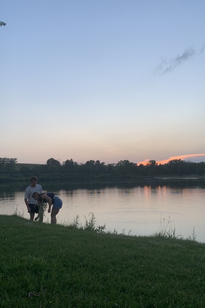 Two people are silhouetted against the twilight sky next to a lake