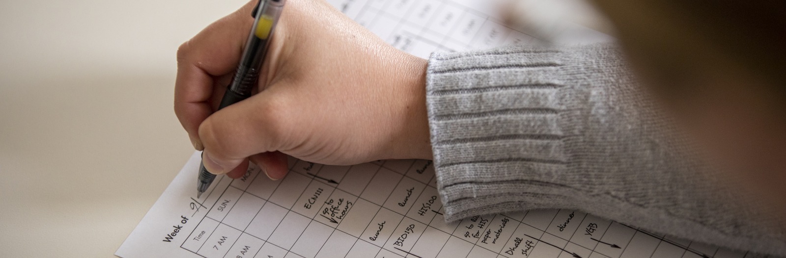 Person writing on paper calendar