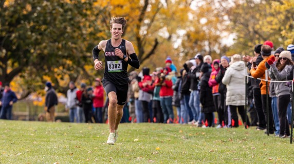 A smiling cross country runner races to the finish line
