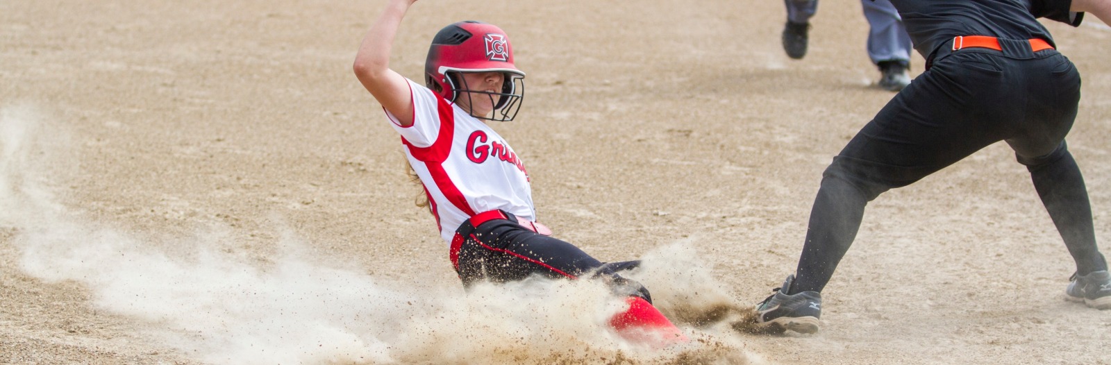 Softball player slides into home plate