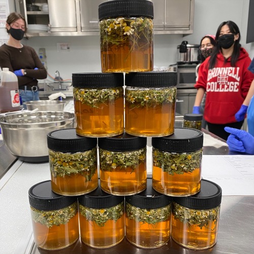 Jars of herbal formulas with students in background