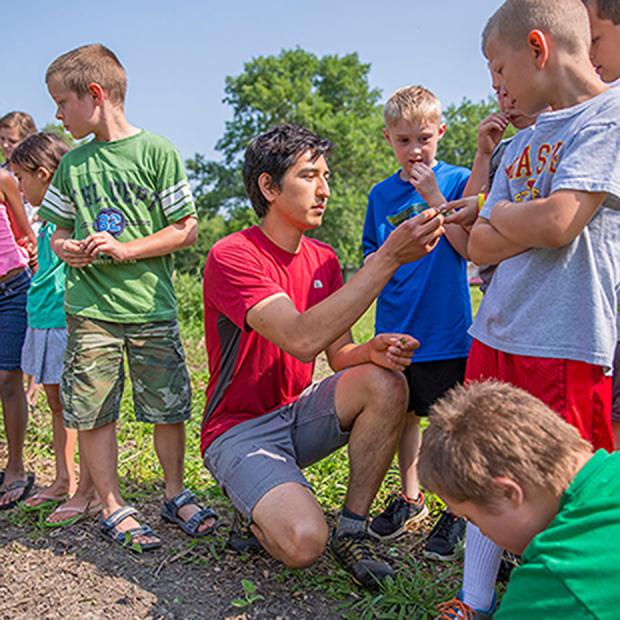 Student teaching children how to garden
