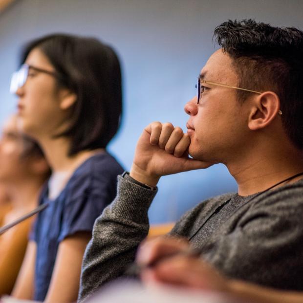 Student listens with hand on chin