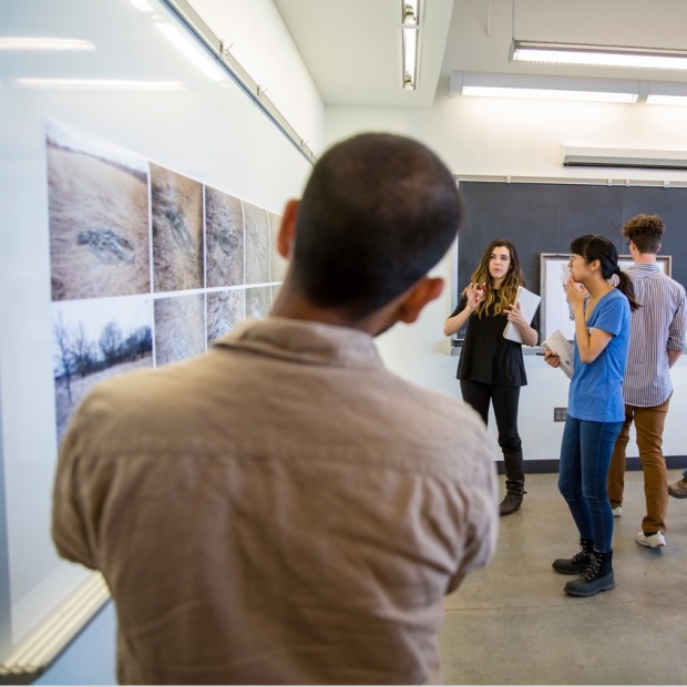 Students stand at whiteboard examining artwork