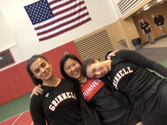 Mia has her arms around her two track friends. They are smiling together in a photo