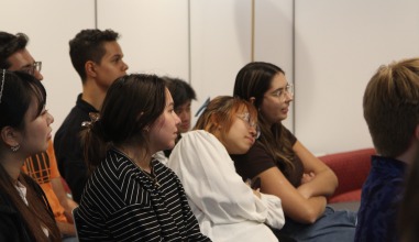 Two students lean against each other as a student presents.