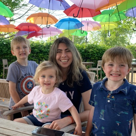 three kids with a student color unbrellas above 