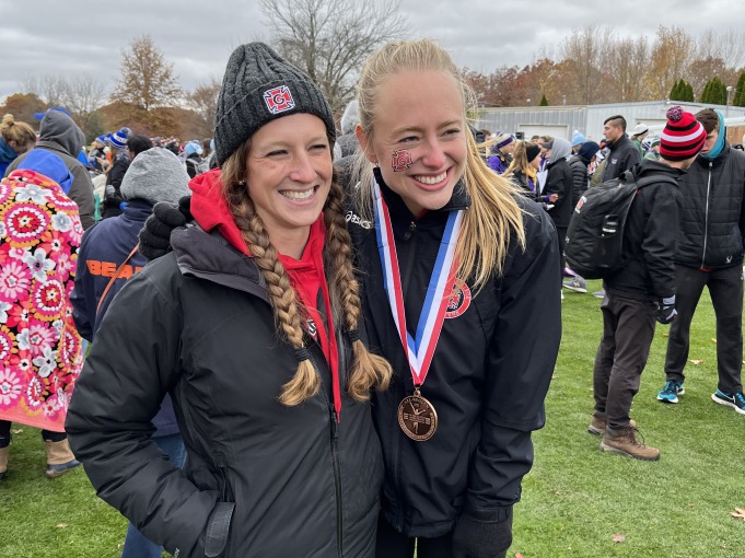 My coach, Sarah Burnell, and I smile in front of the camera after the meet. I have a medal on my neck