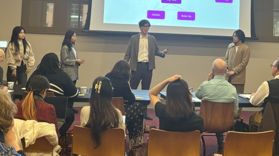 Four students with a flowchart slide during presentation to a panel of event judges.