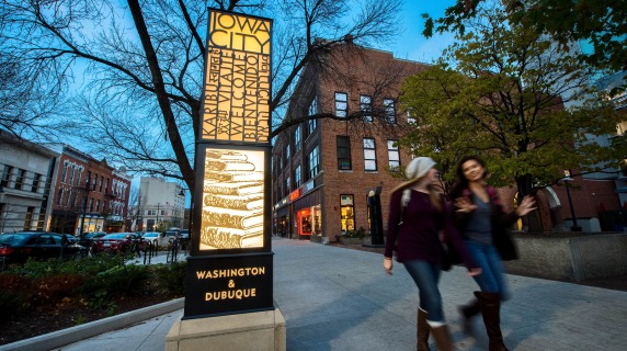 Iowa City sidewalk pic with two peoples by a street sign
