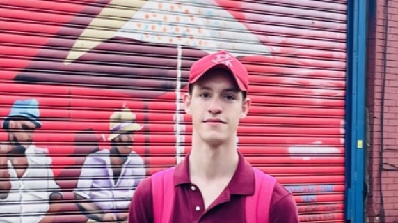 Jack Thornton stands, hands in pockets, in front of a colorful mural