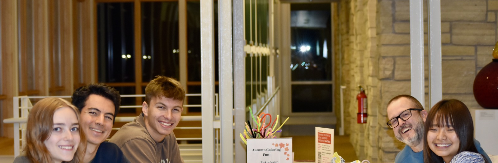 5 people sitting around a table smiling 