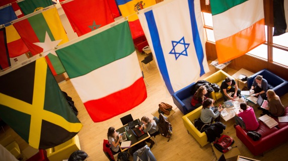 Students chat together under the global flags in Spencer Grill