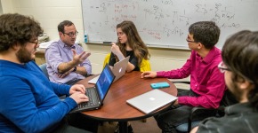 Students sit at table with professor