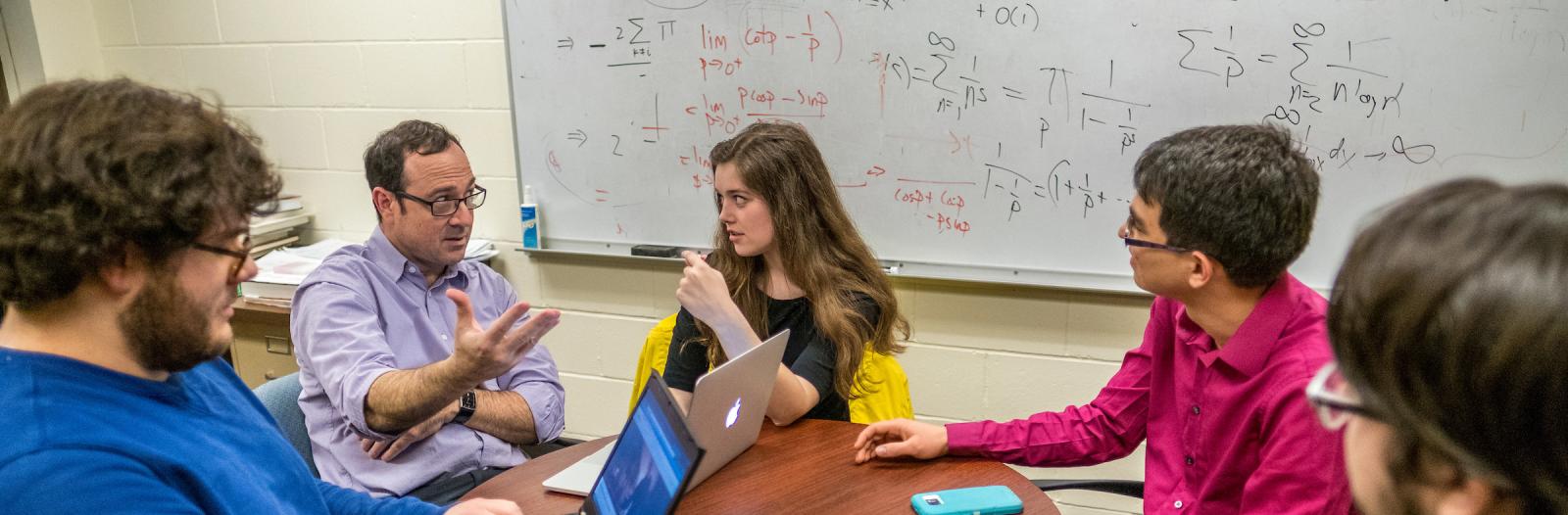 Students sit at table with professor