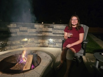 Mykenzie sits near a stone firepit